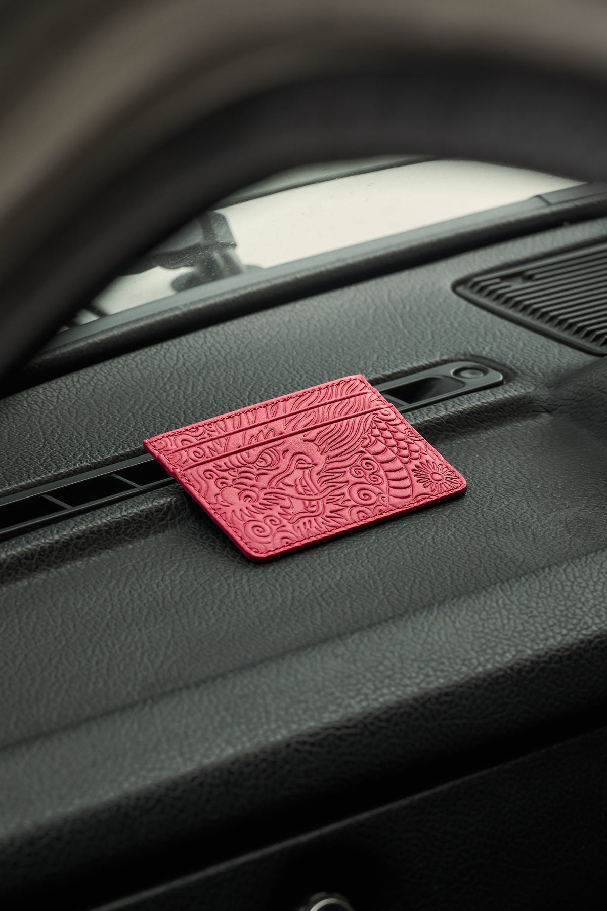 Crimson Ryu leather card holder resting on a car dashboard
