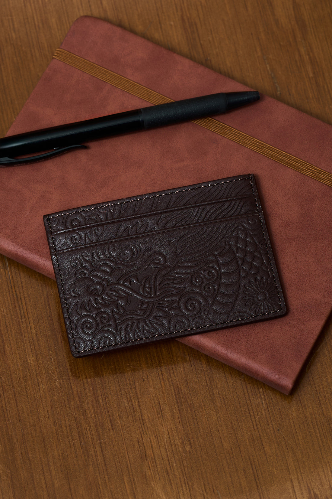 Mocha Ryu card holder with embossed dragon detail on a notebook